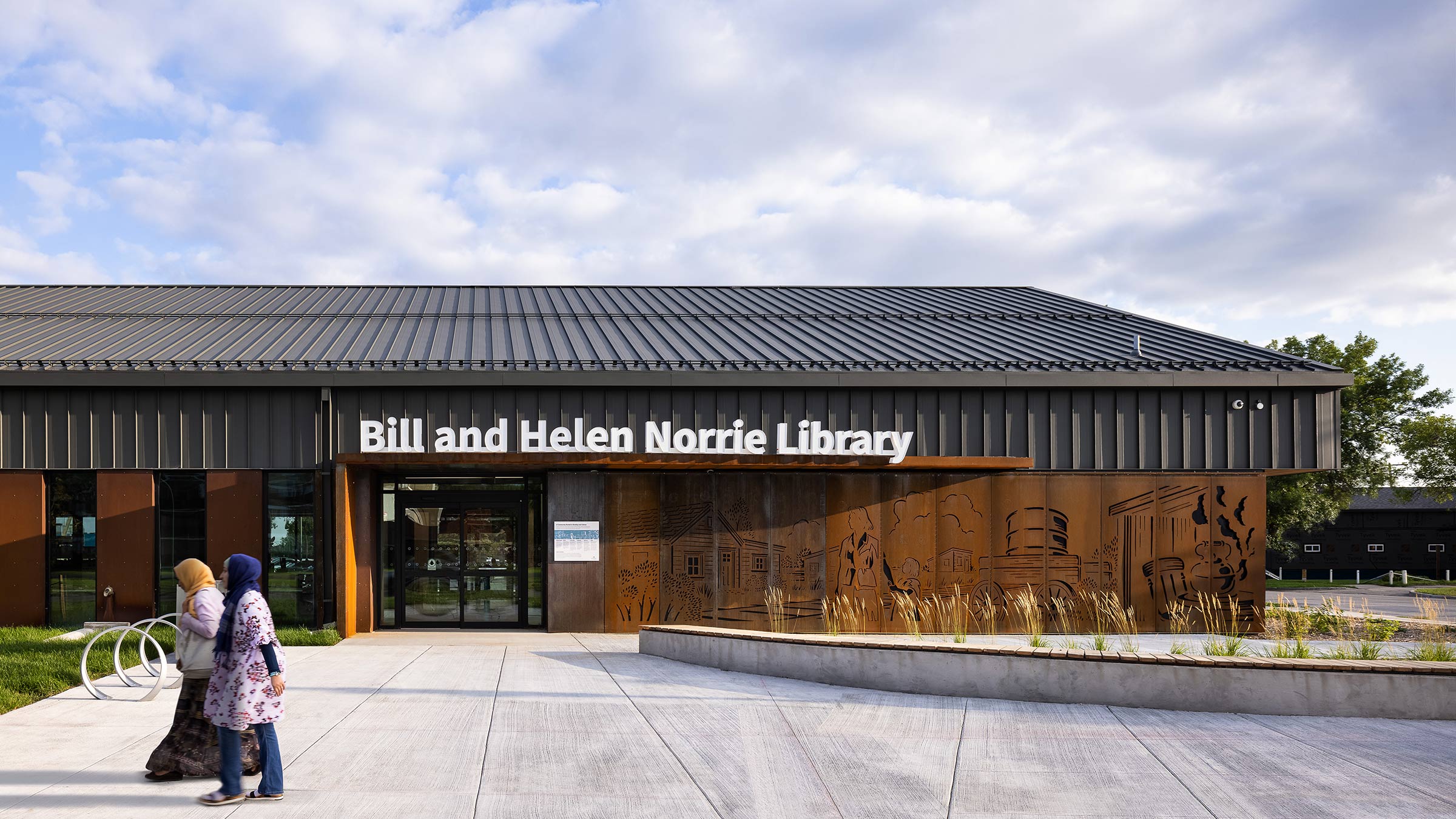 Close up of the exterior of Bill and Helen Norrie Library with people walking past.